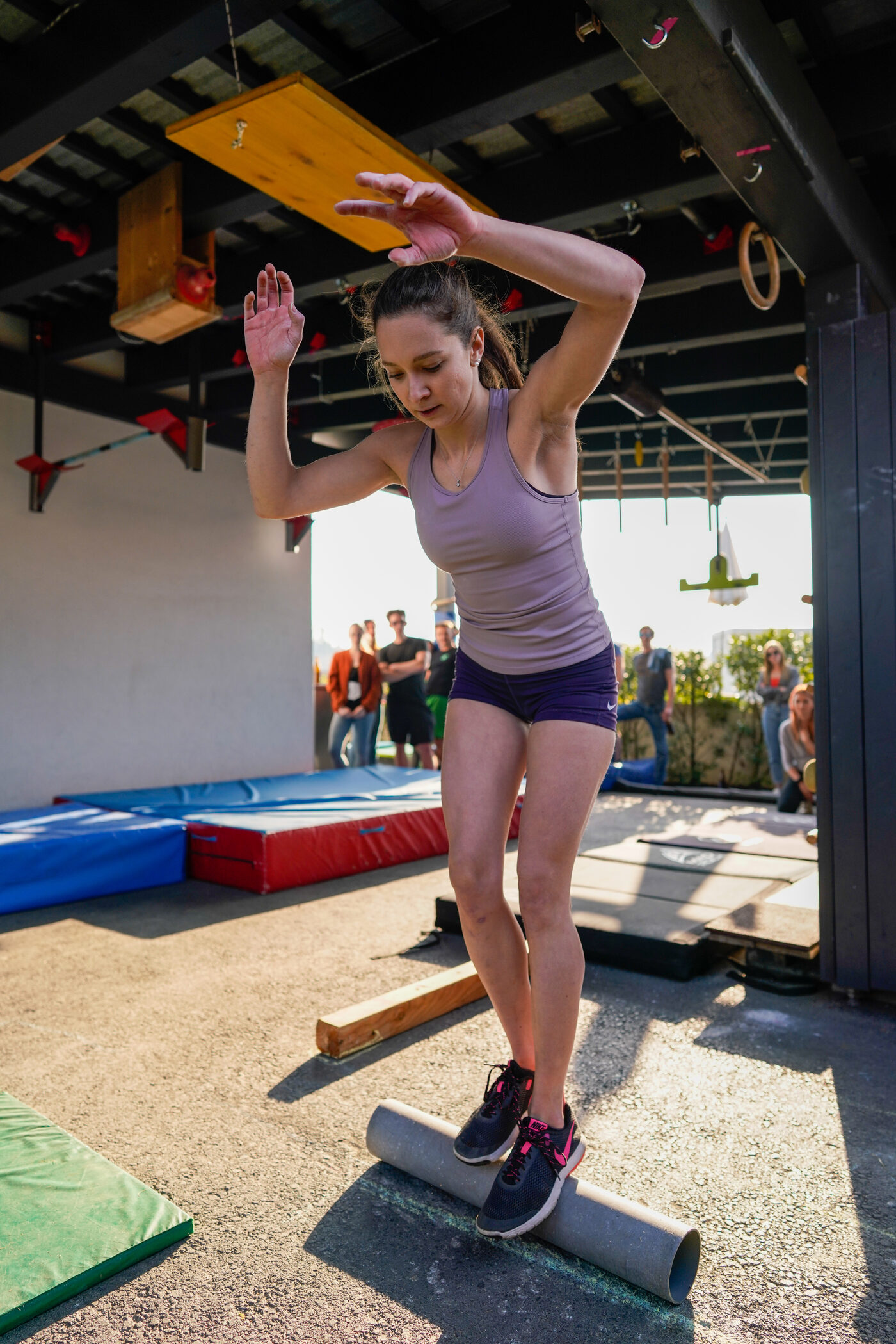 Athletin balanciert auf einem Rohr bei einer Challenge