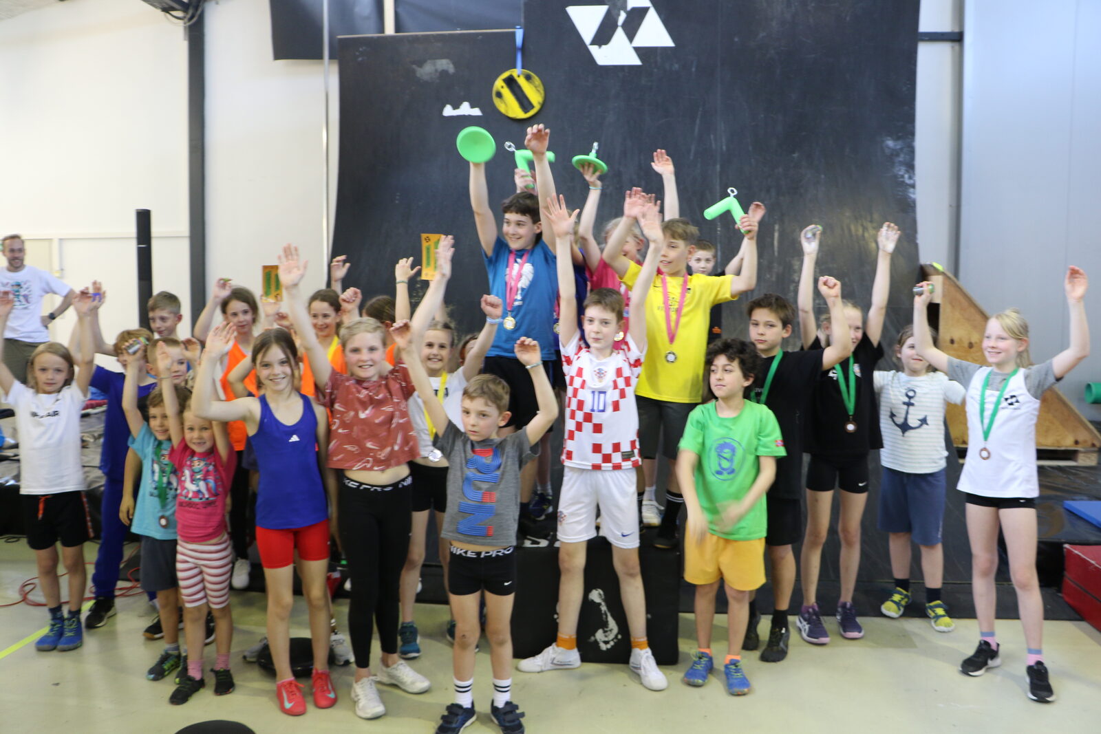 Gruppe von Kindern mit erhobenen Armen und Medaillen nach einem Kids-Bewerb