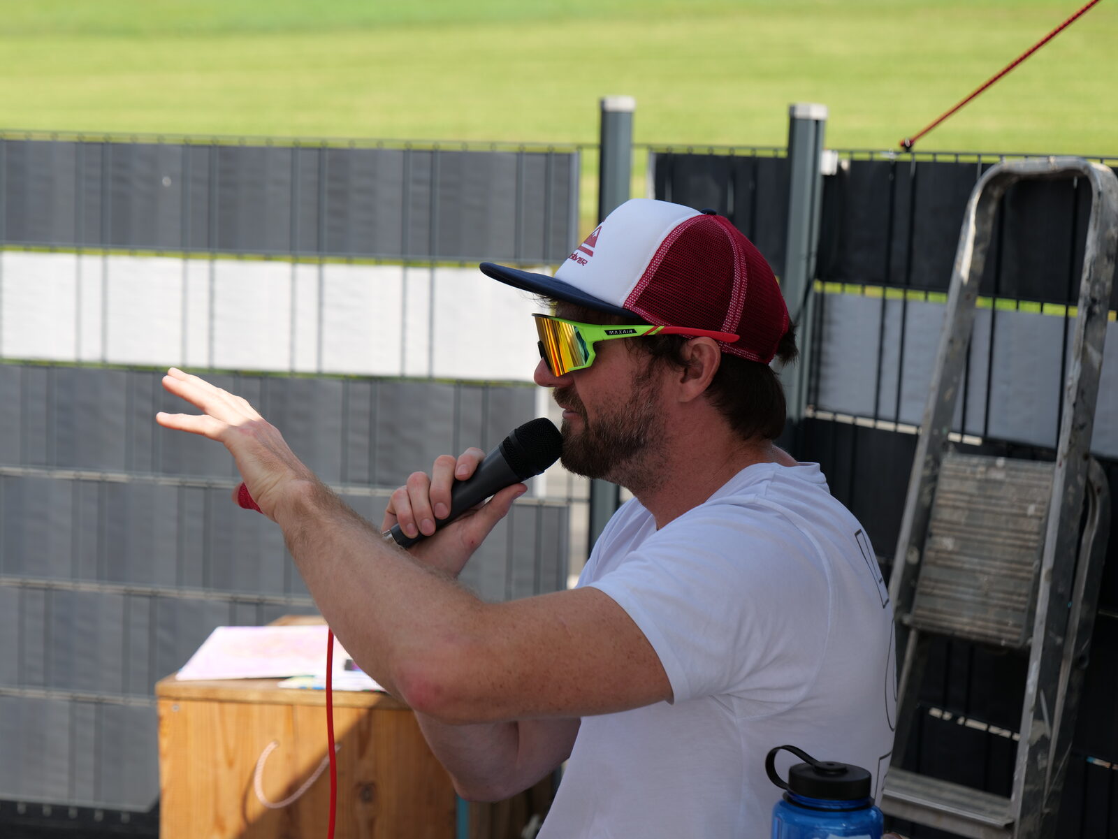 Moderator mit Mikrofon und Kappe im Sonnenschein