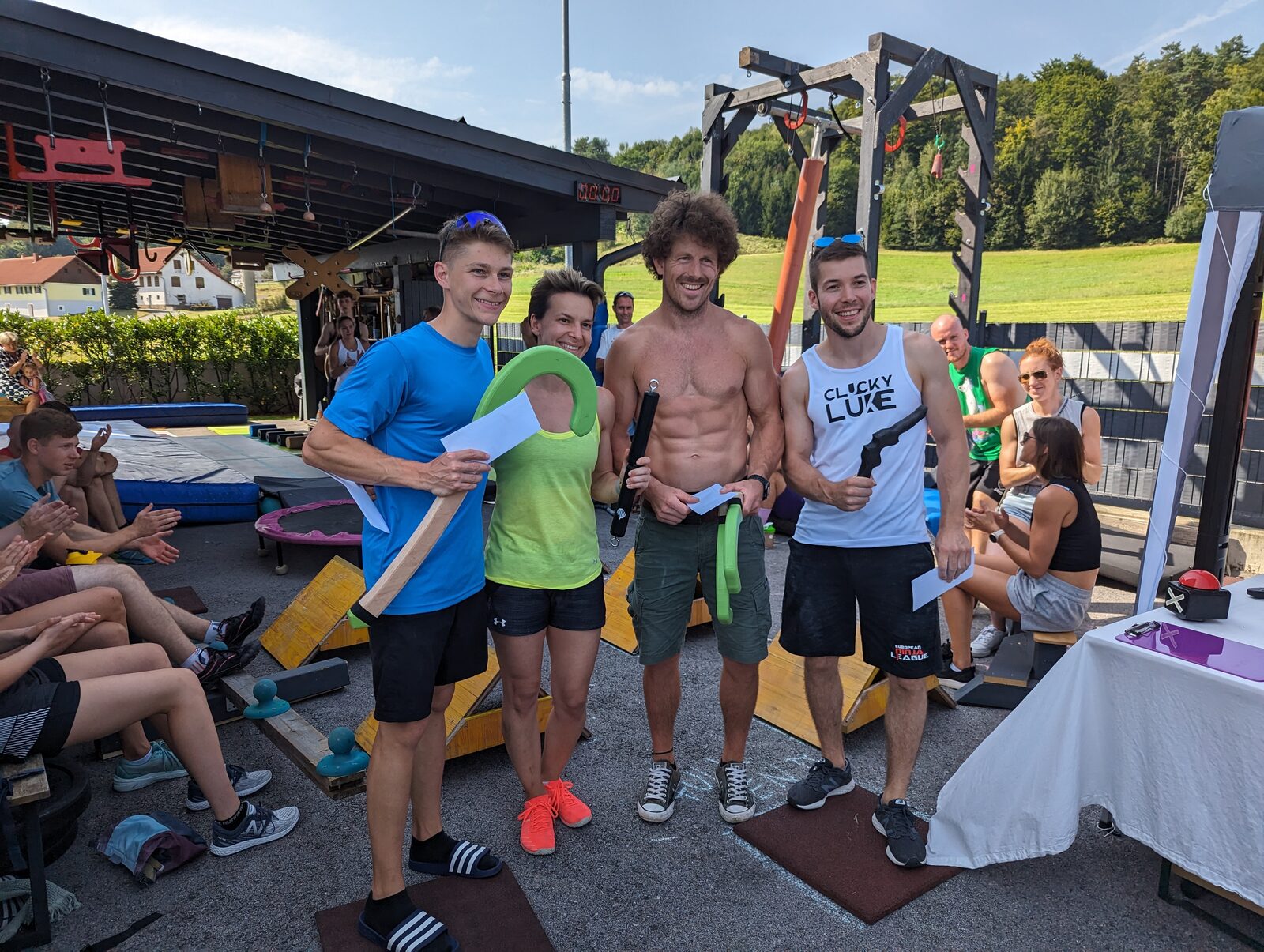 Vier Sieger:innen auf dem Podium mit Trophäen und Urkunden