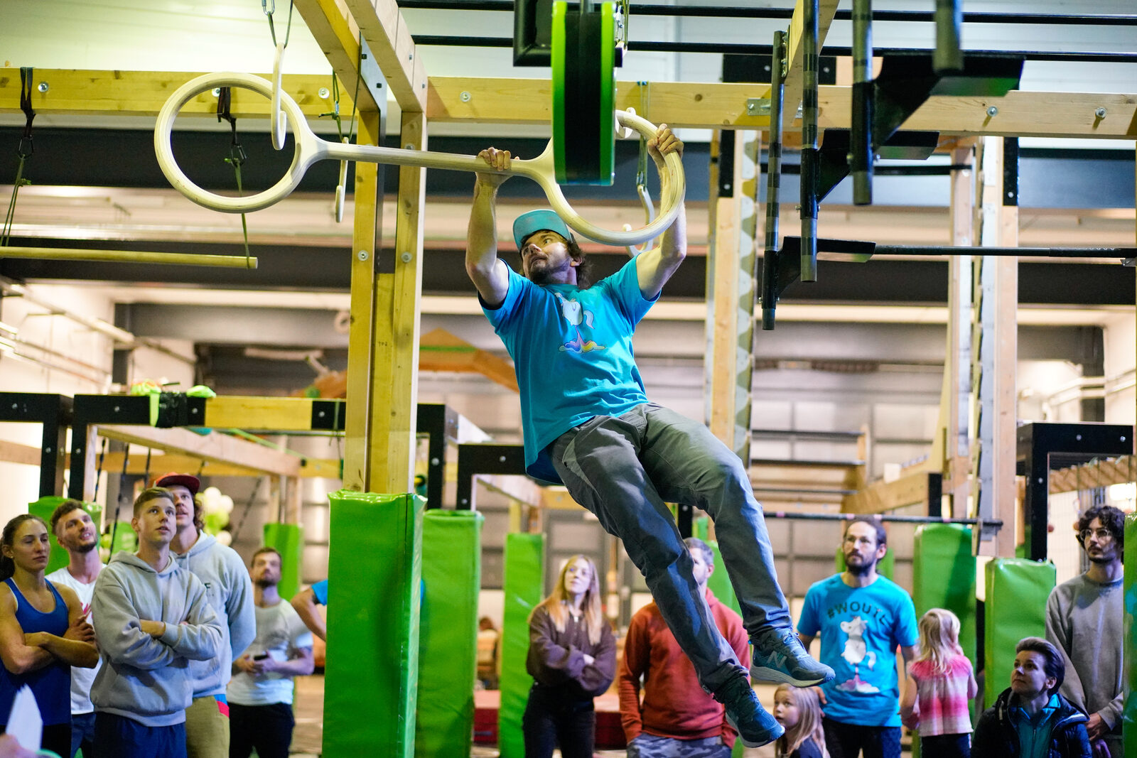 Athlet hängt an einem Ring-Obstacle in der Halle