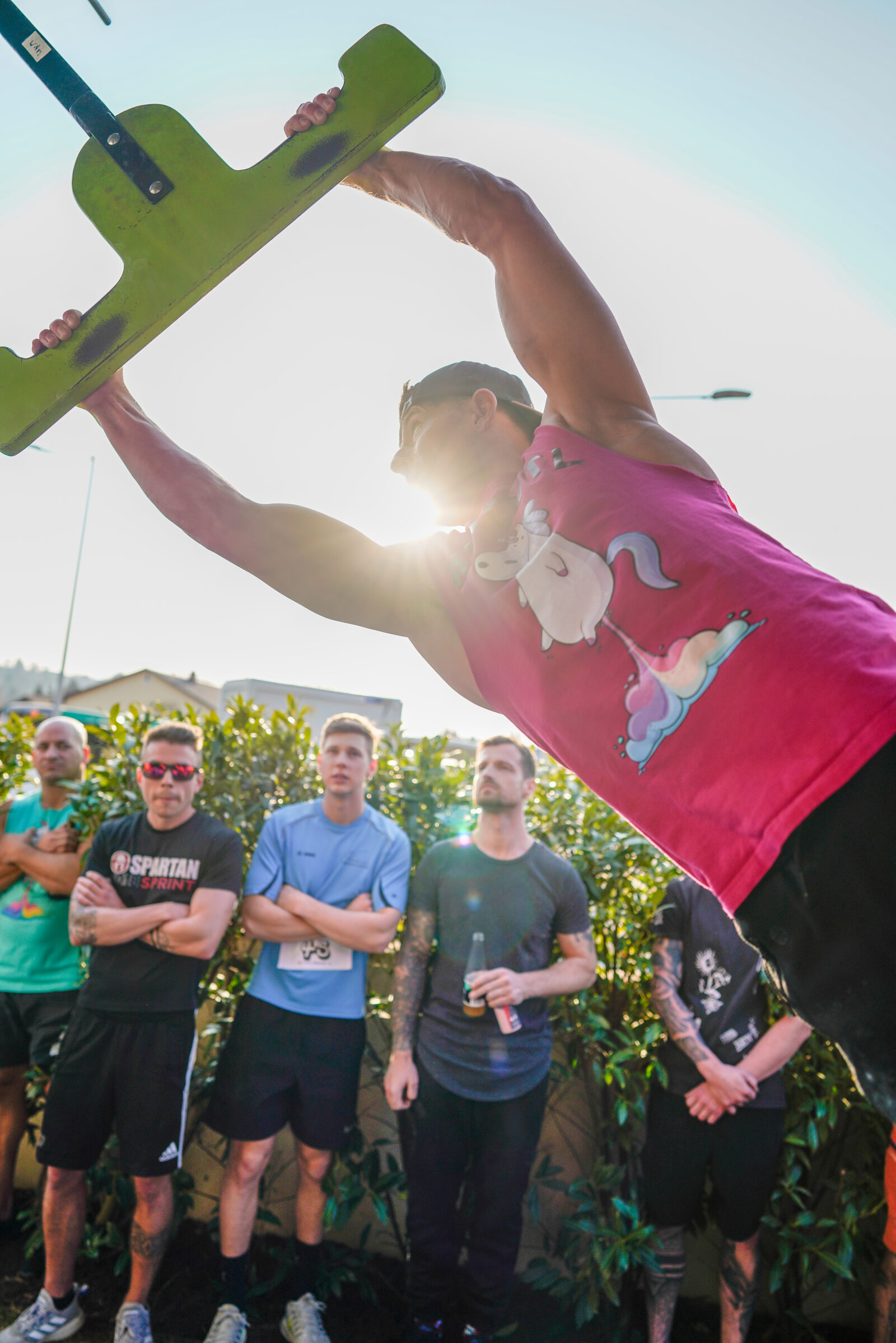 Athlet im Gegenlicht mit grünem T-Obstacle bei einem Ninja-Bewerb